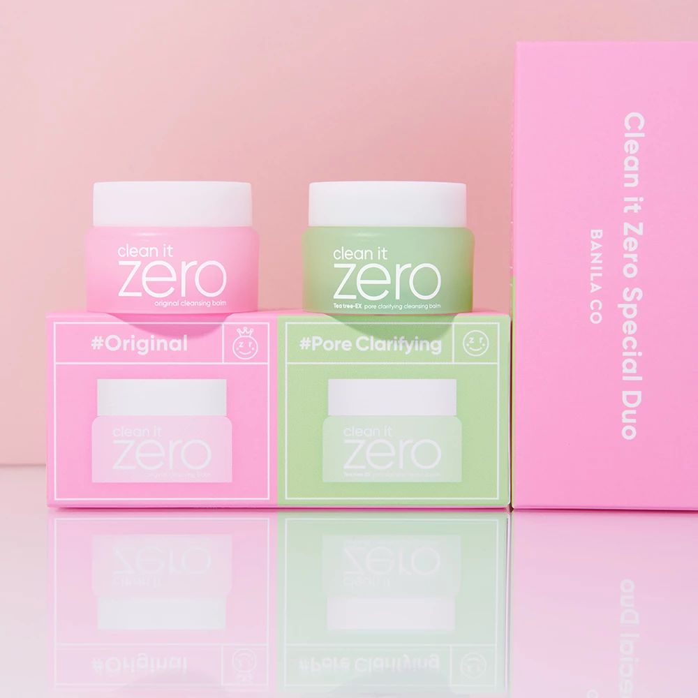 Zwei Clean It Zero Tiegel, einer rosa für Original, einer grün für Pore Clarifying, auf ihren jeweiligen Verpackungen.