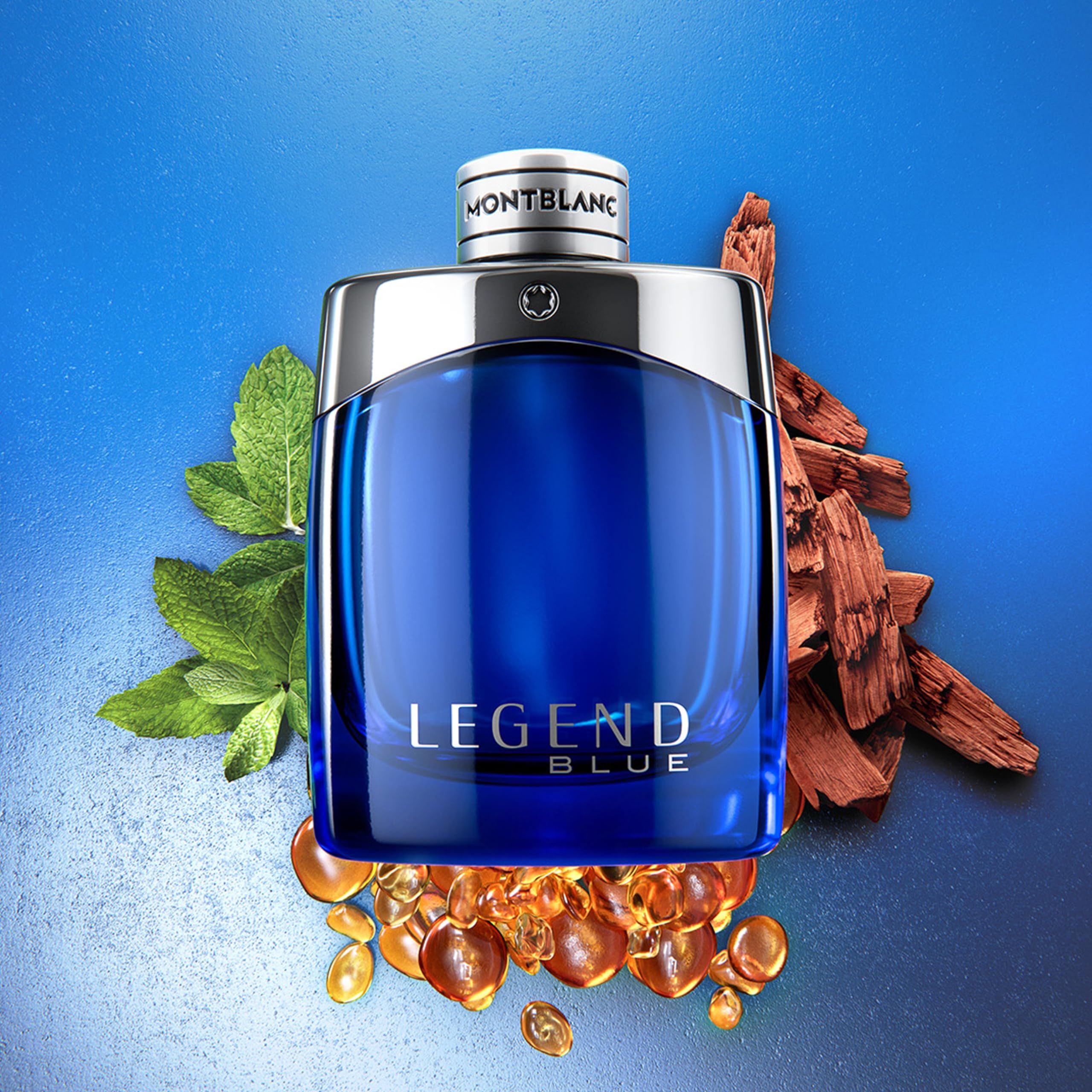 Blauer Montblanc Legend Blue EdP-Flakon. Silberne Kappe. Dekoration mit Blättern und Holzstücken.