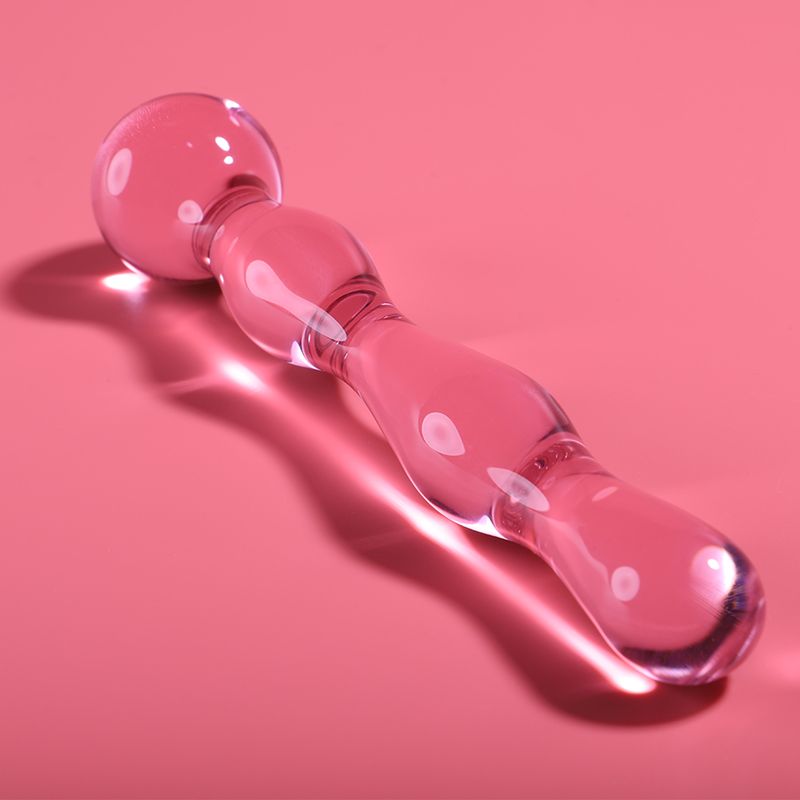 Rosa Dildo aus Borosilikatglas. Kugel am oberen Ende, länglicher Schaft mit Verdickungen. Liegt auf rosa Untergrund.