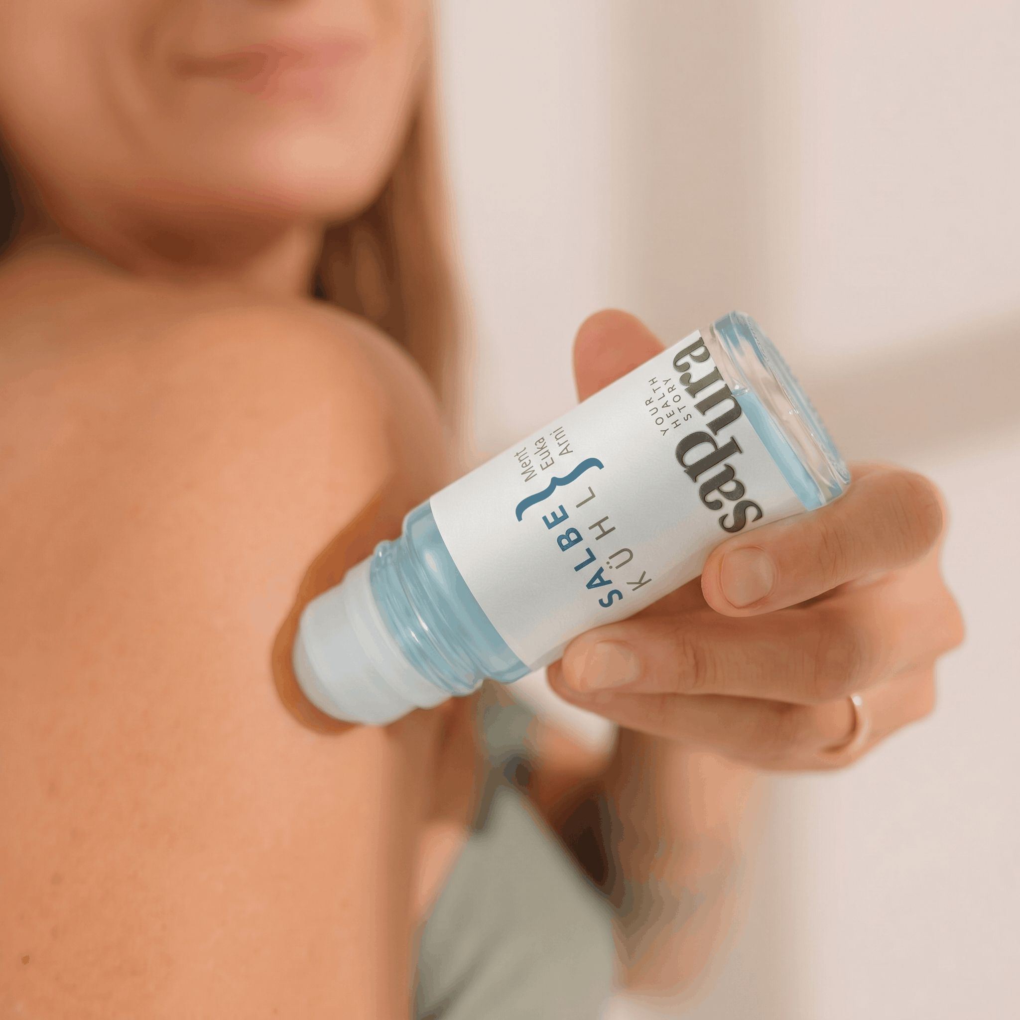 Hand rollt sapura health® Kühlgel Roll-On auf die Schulter.