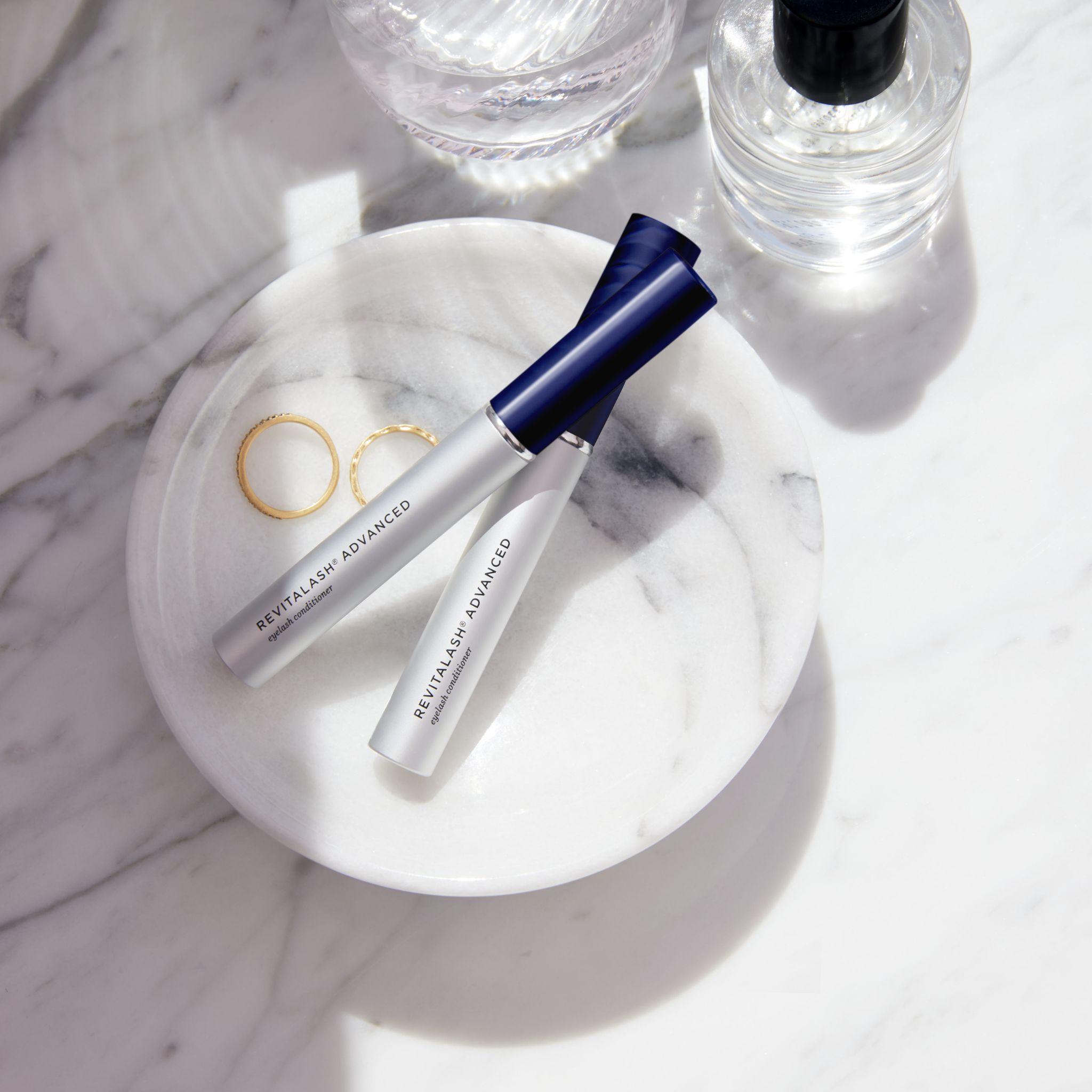 Zwei silberne Fläschchen mit blauem Deckel, beschriftet mit 'RevitaLash Advanced'.