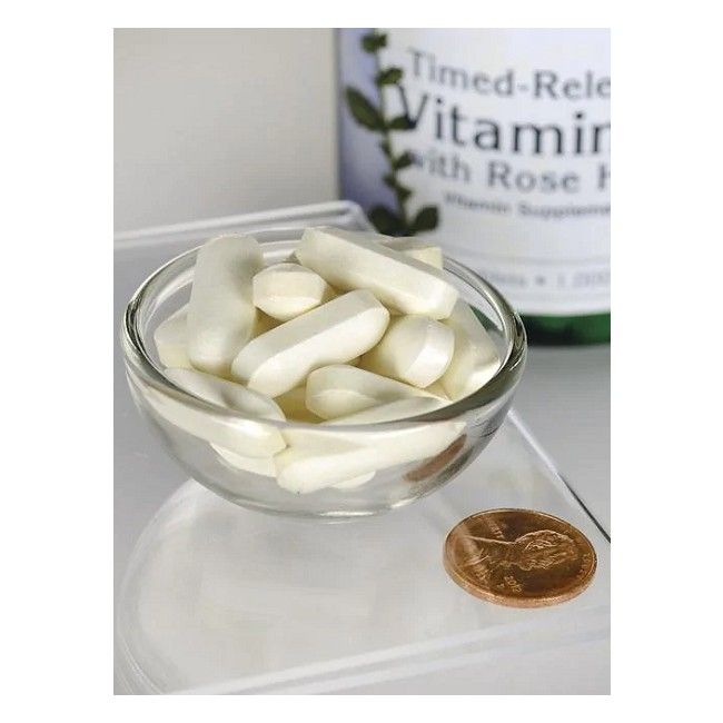 Klare Glasschale mit weißen Tabletten. Daneben eine Münze. Im Hintergrund eine Flasche mit Produktetikett.