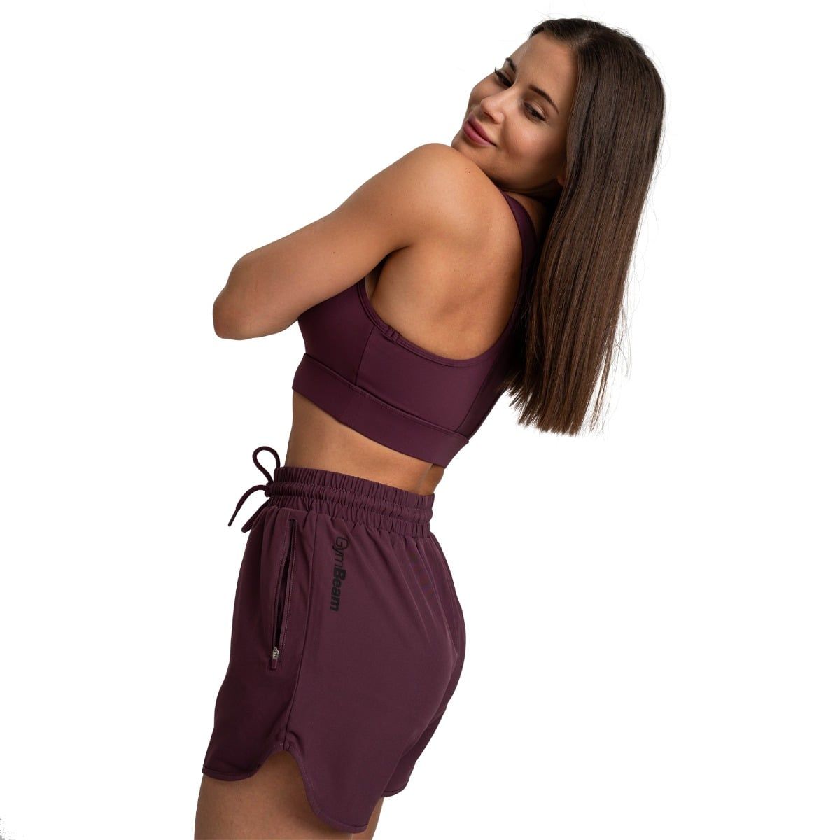 Frau in Aubergine Sport-BH und Shorts mit Kordelzug, Pose.