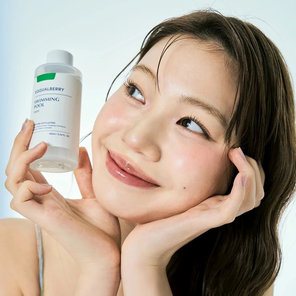 Frau hält eine Flasche Toner. Produktetikett sichtbar. Hellblauer Hintergrund.