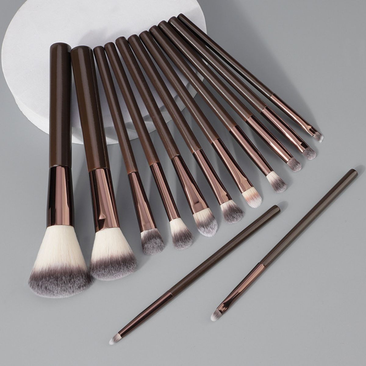 Ein Set aus elf braunen Make-up-Pinseln mit metallischen Applikationen und weichen Borsten.