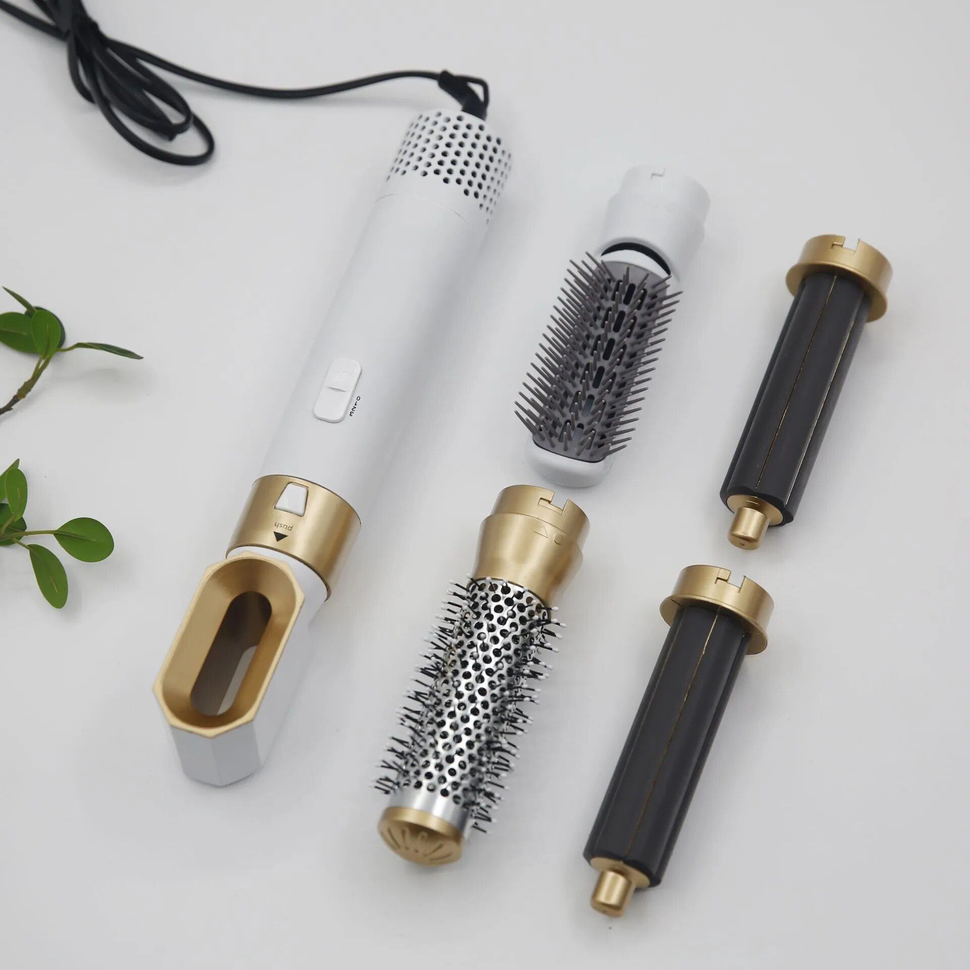 Haarstyling-Revolution mit weißem Griff, goldenen Akzenten und mehreren Aufsätzen. Enthält Bürsten und Zylinder.