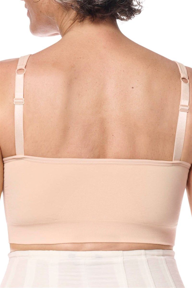 Rückansicht eines beigefarbenen BHs. Breite Träger, nahtloser Stoff. Frau trägt den BH.