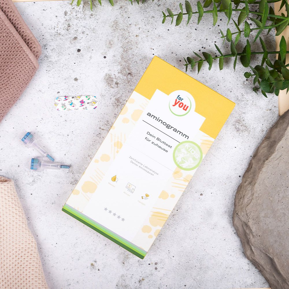 Aminogramm Kids Bluttest-Verpackung auf einem Tisch mit Zubehör.
