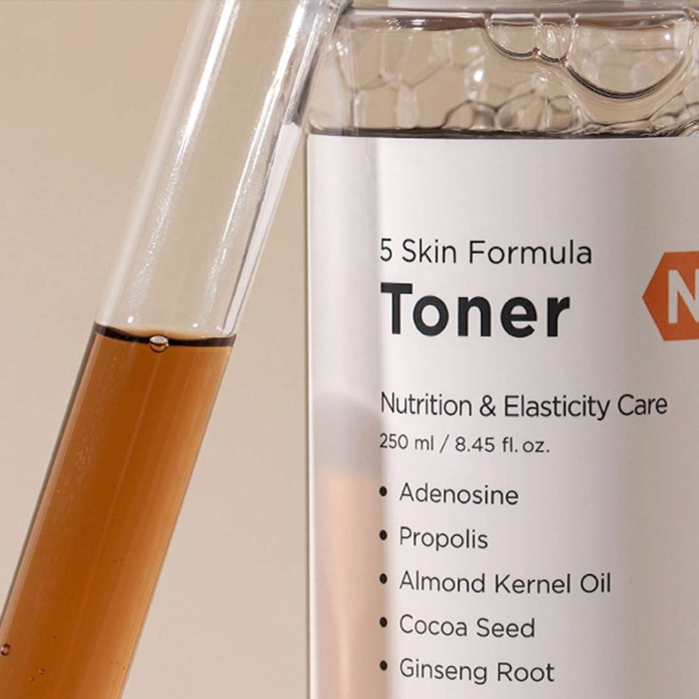 Nahaufnahme einer Flasche mit Etikett: Toner, 5 Skin Formula, N. Braune Flüssigkeit. Reagenzglas mit Flüssigkeit daneben.