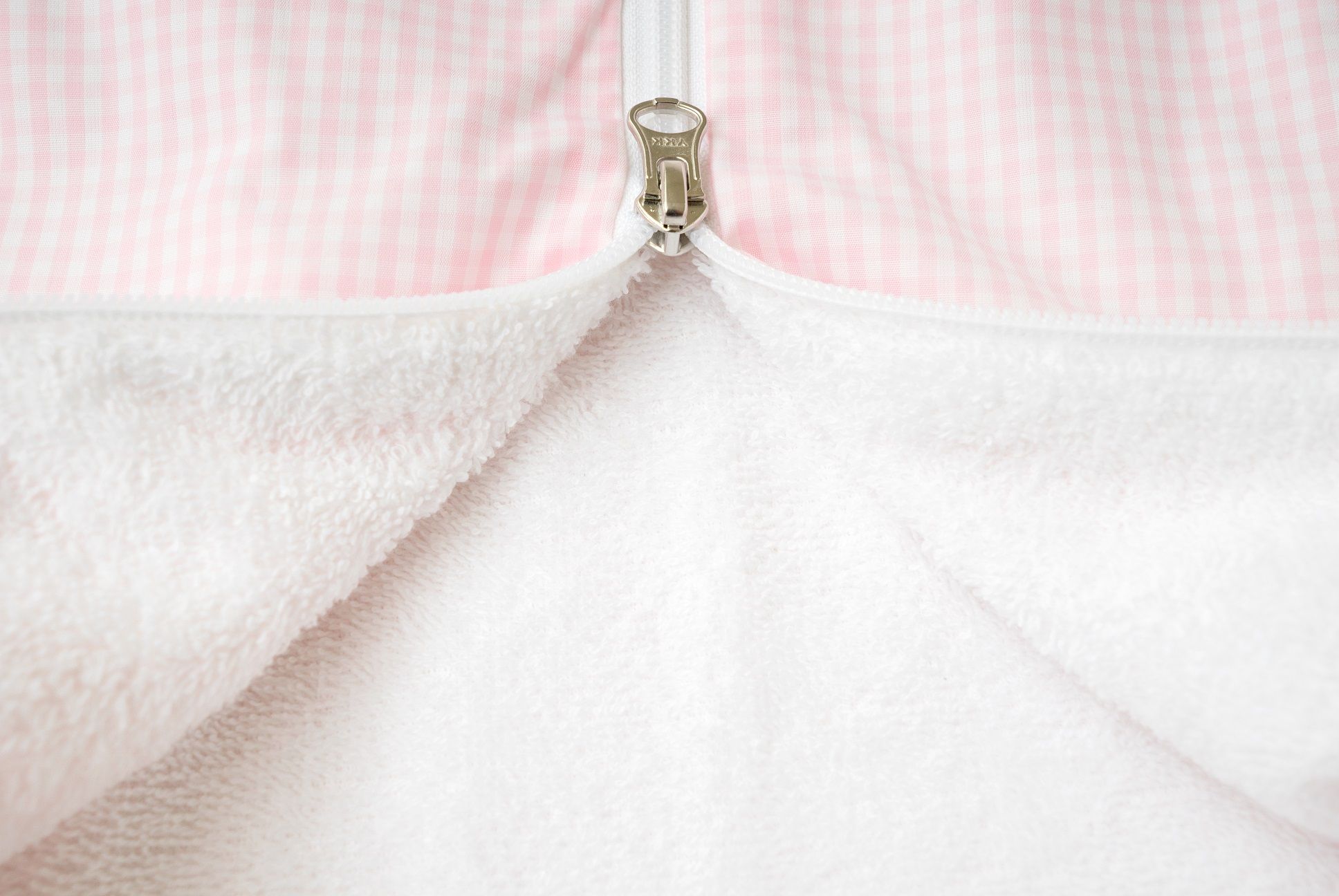Nahaufnahme des Reißverschlusses eines rosa Schlafsacks. Innenfutter aus weißem Frottee.