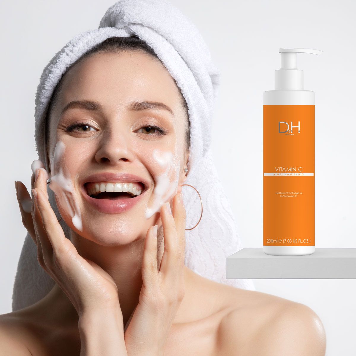 Frau mit Schaum im Gesicht und Flasche mit Pumpe. Aufschrift: D.H. Vitamin C Anti-Aging. Weiße Schrift auf orangefarbenem Hintergrund.