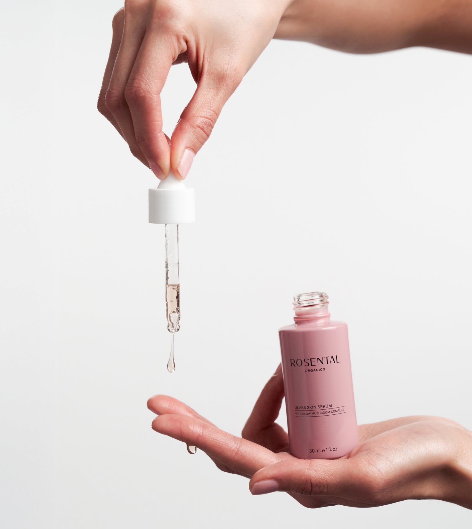 Hände halten Flasche und Pipette. Serum tropft aus der Pipette.