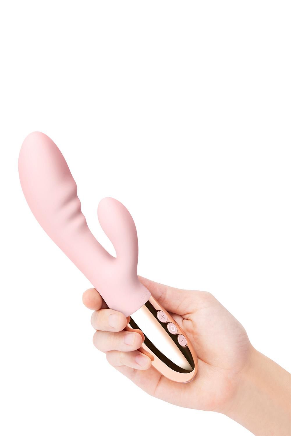 Rosa Vibrator, gehalten in einer Hand. Goldfarbener Sockel mit drei Knöpfen. Gebogene Form.