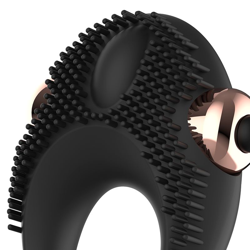 Nahaufnahme des schwarzen Silikon-Vibrator-Penisrings. Erhabene Noppen und zwei roségoldfarbene Elemente.