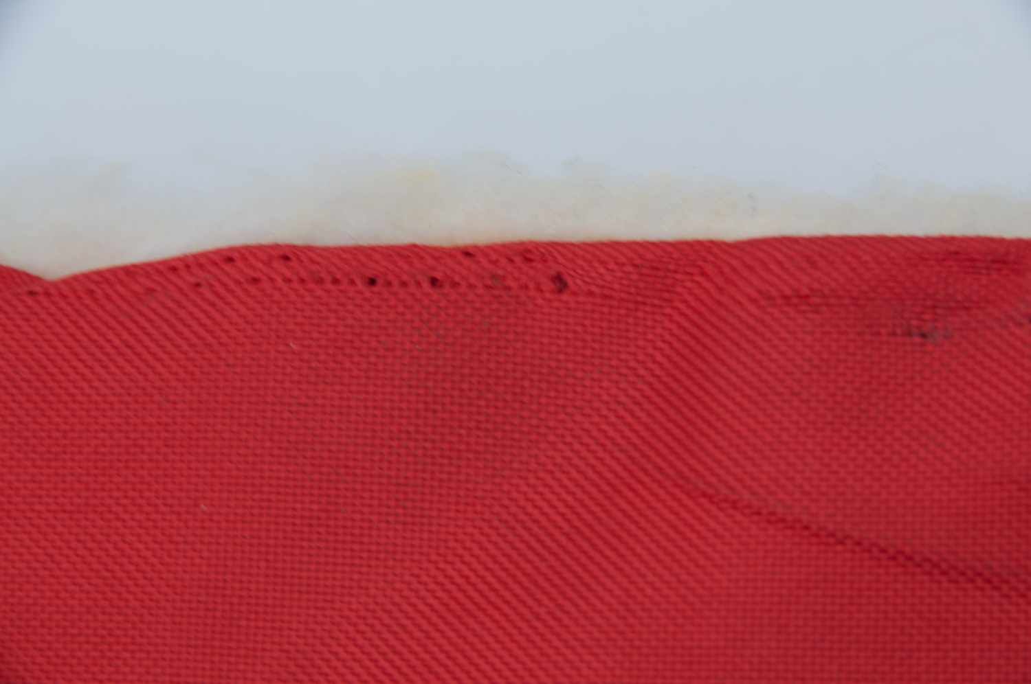Nahaufnahme eines roten Stoffes mit sichtbaren Nähten. Der Stoff ist mit einem weißen Material verbunden.
