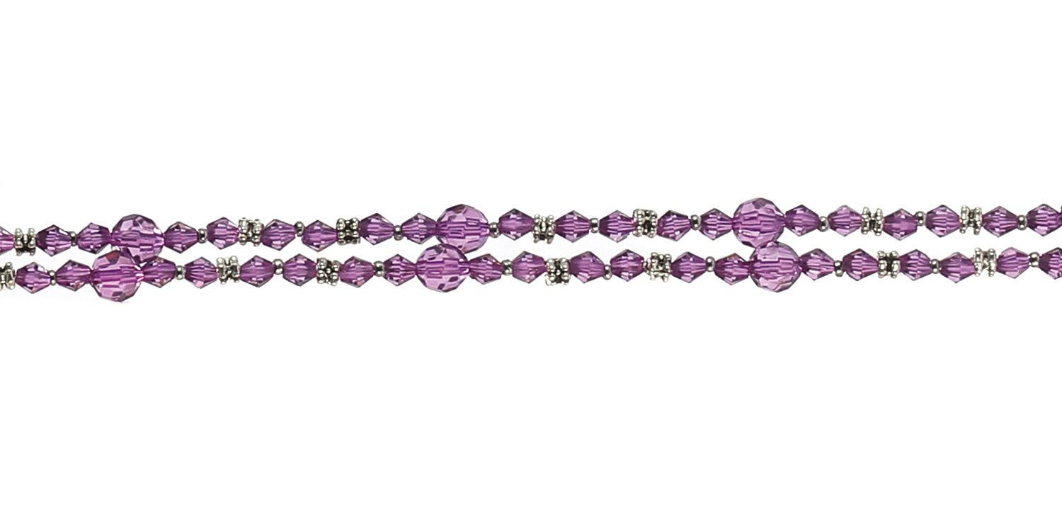 Nahaufnahme einer Brillenkette mit violetten Perlen und silberfarbenen Elementen. Zwei Stränge, horizontal angeordnet.