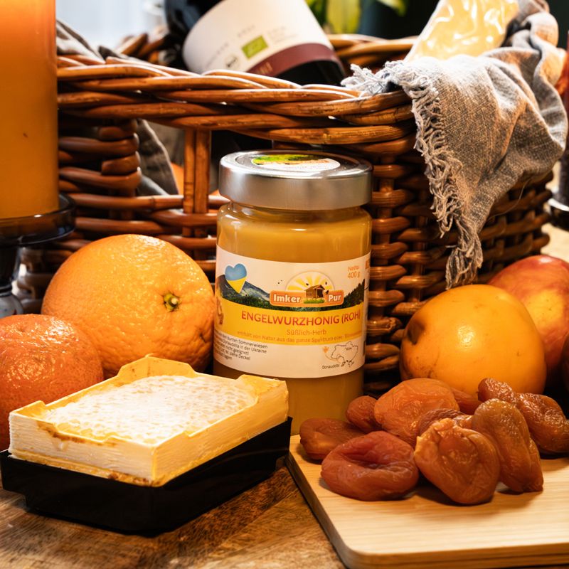 Korb mit ImkerPur Engelwurzhonig (roh), Obst, Käse und Wein. Honigglas mit Etikett.