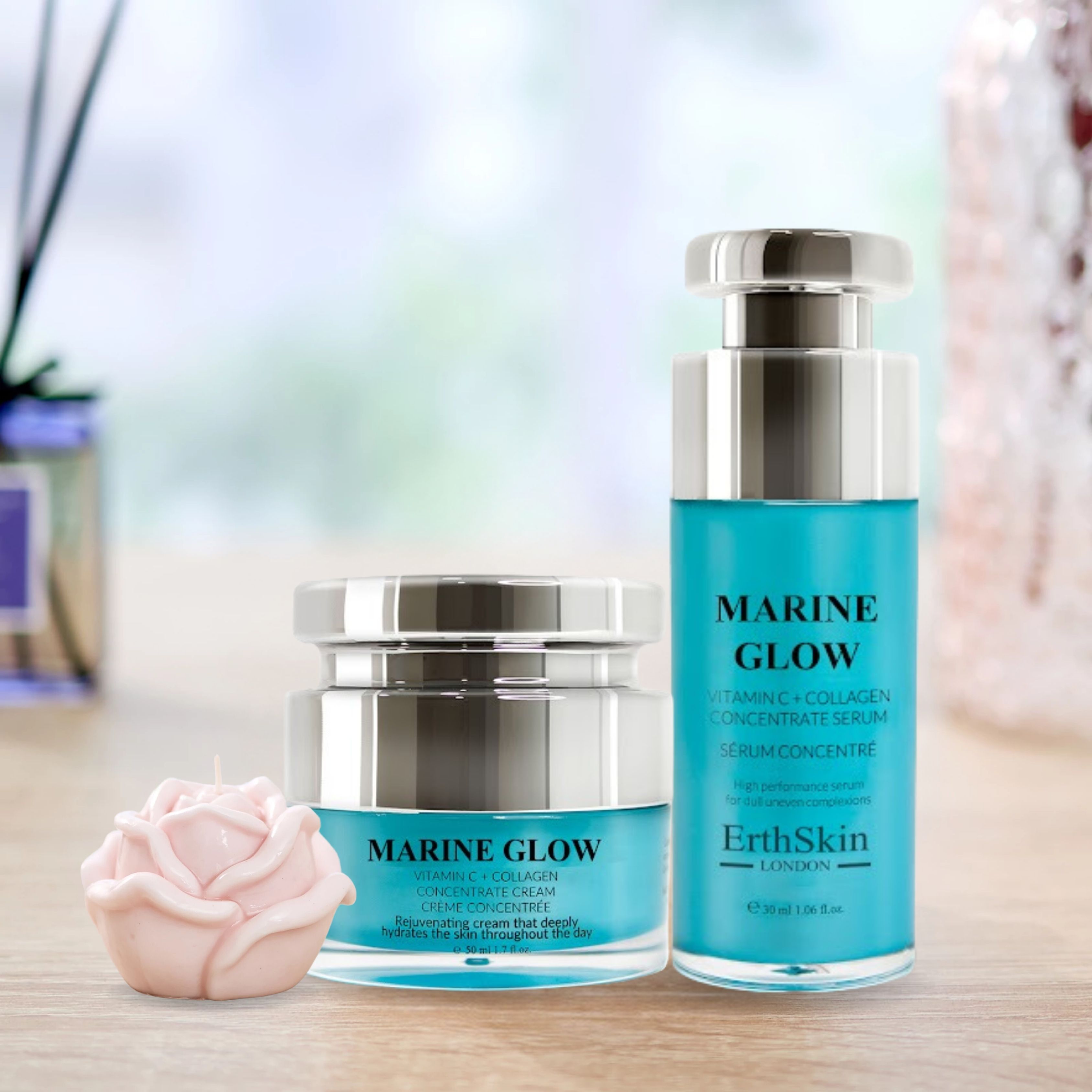 Zwei blaue Flaschen mit silbernen Deckeln. Aufschrift: Marine Glow, Vitamin C + Kollagenkonzentrat-Serum und Creme. Marke: ErthSkin London. Eine rosa Kerze.