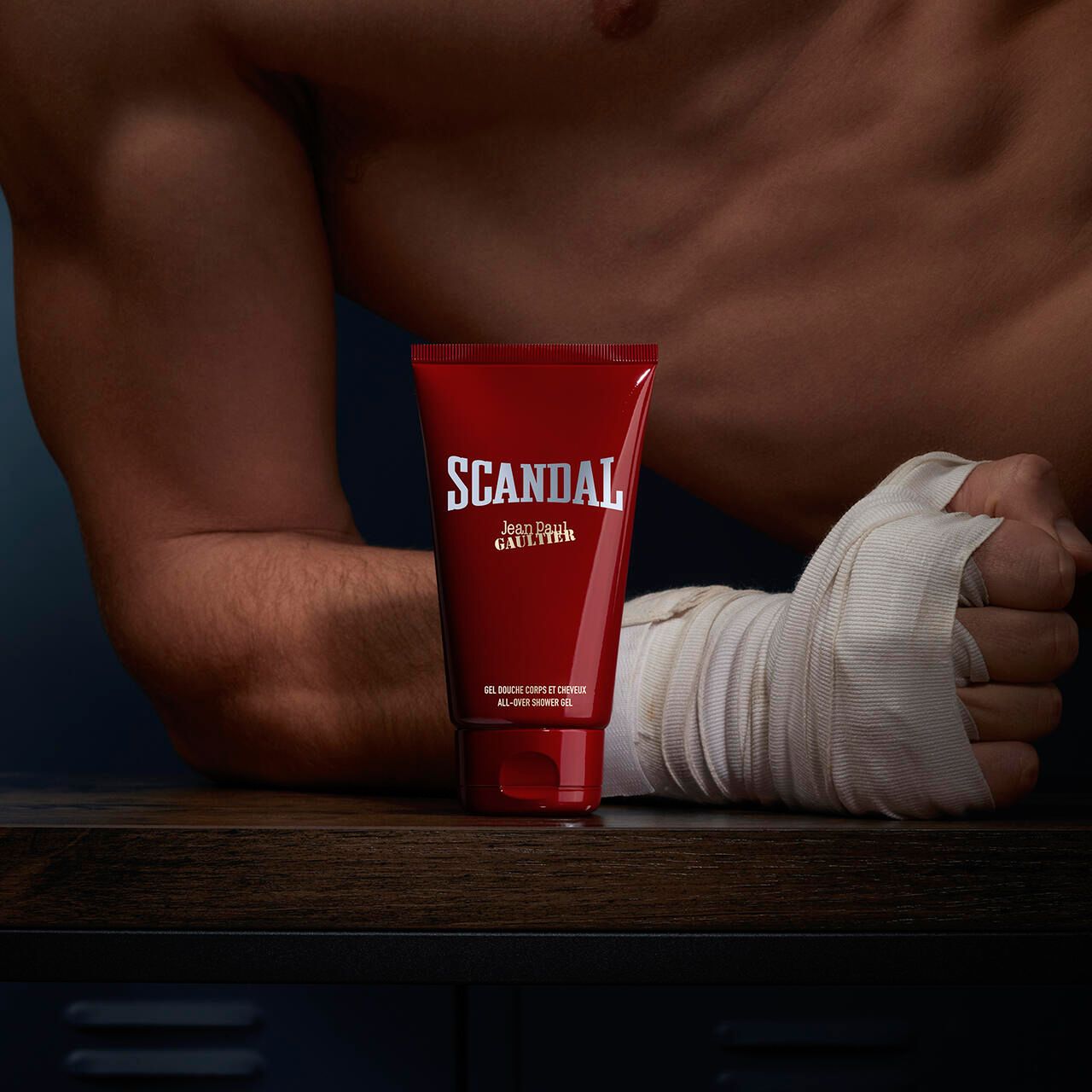 Rote Tube mit "SCANDAL" und "Jean Paul Gaultier" Schriftzug. Vor Arm mit Bandagen.