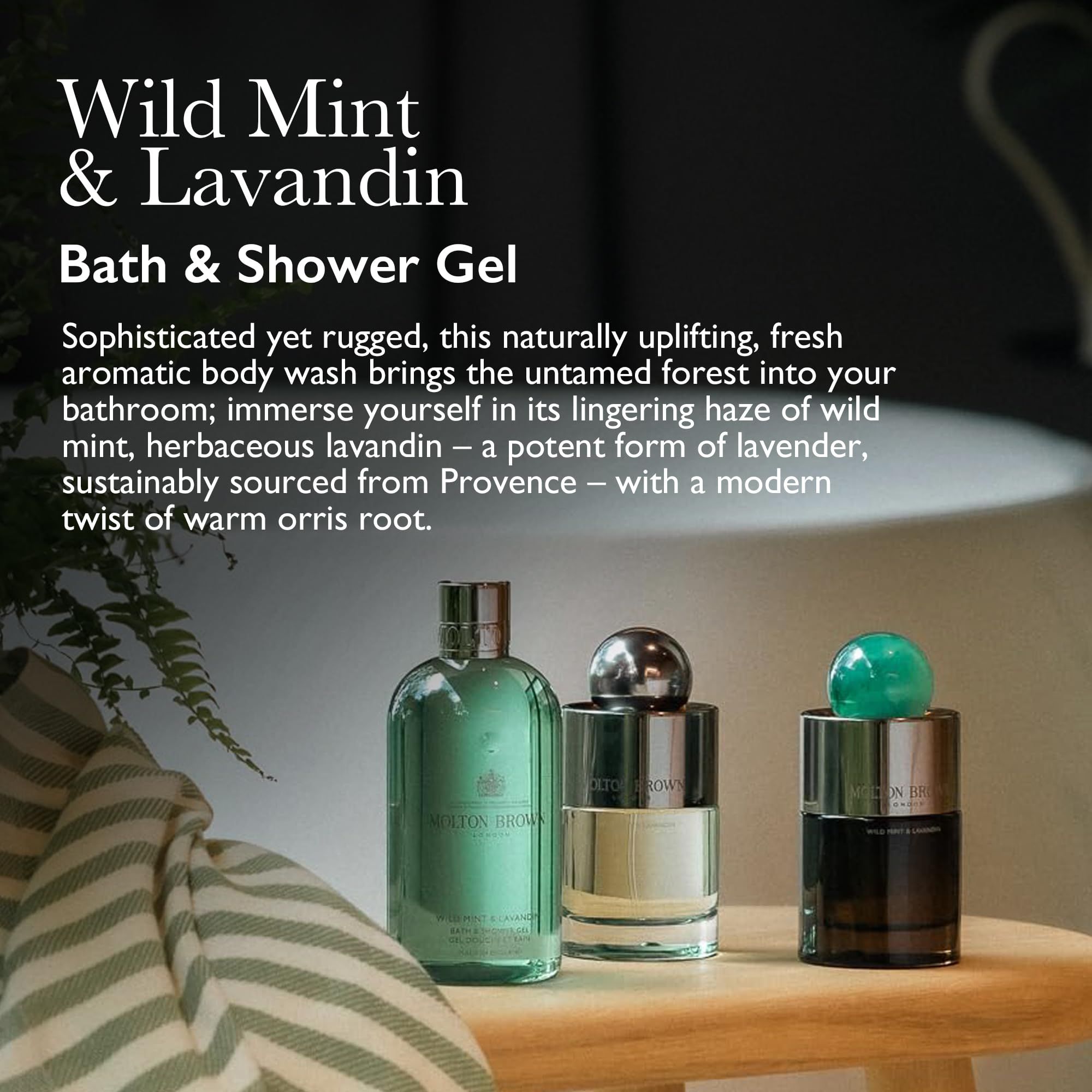 Molton Brown Wild Mint & Lavandin Bade- & Duschgel in Flaschen auf einem Holzhocker mit Handtuch.