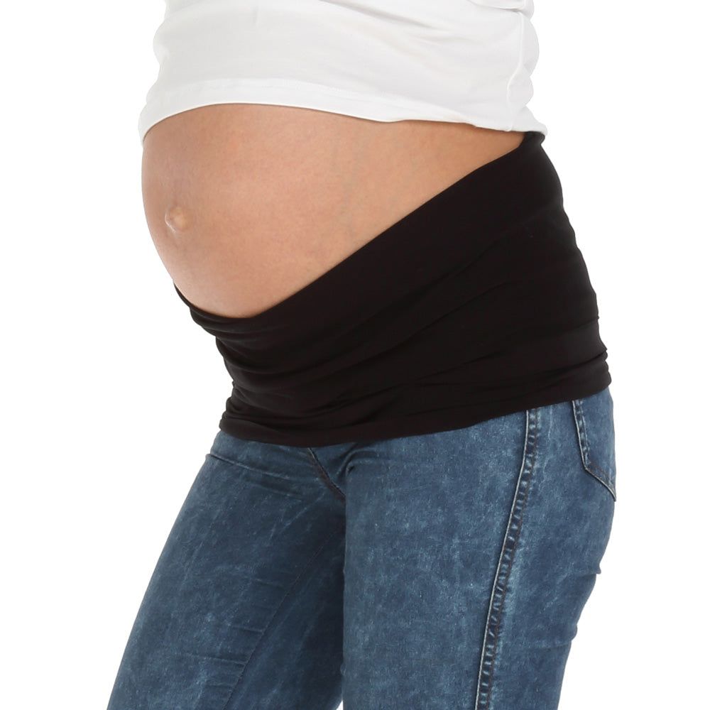 Schwarzes Bauchband, getragen von einer Person mit Schwangerschaftsbauch. Sichtbar: Jeans, weißes Oberteil.