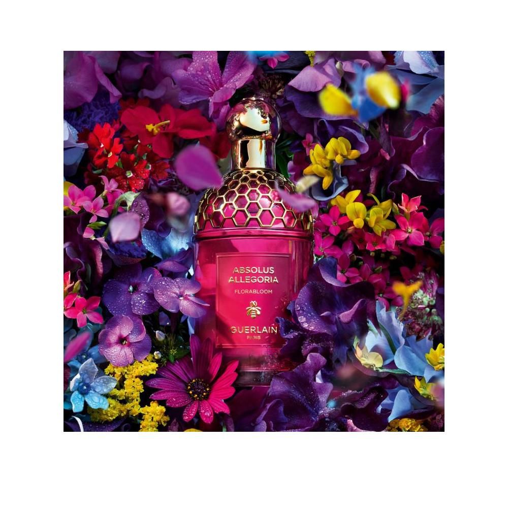 Parfümflakon in Blumenarrangement. Aufschrift: Absolus Allegoria Florabloom, Guerlain Paris. Goldener Deckel.