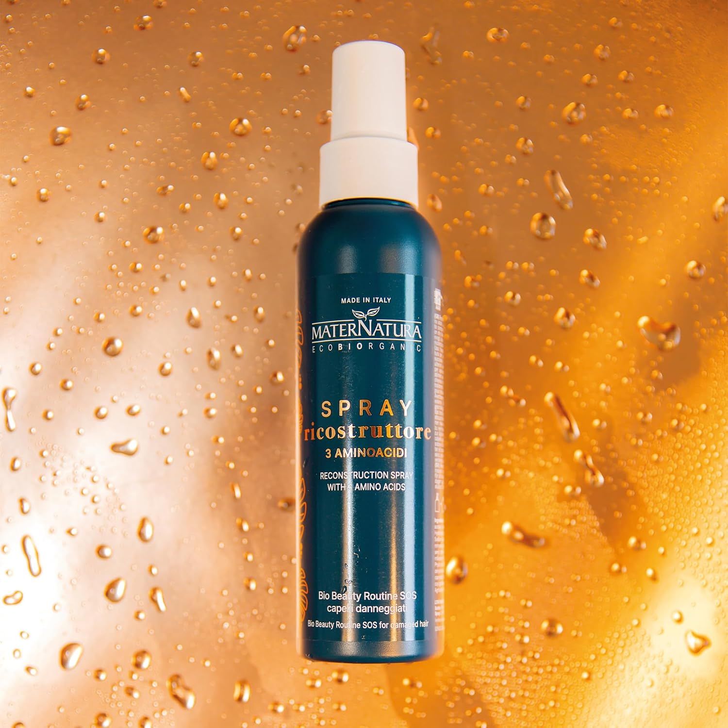 Flasche MaterNatura Spray Ricostruttore mit Aminosäuren auf goldenem Hintergrund.