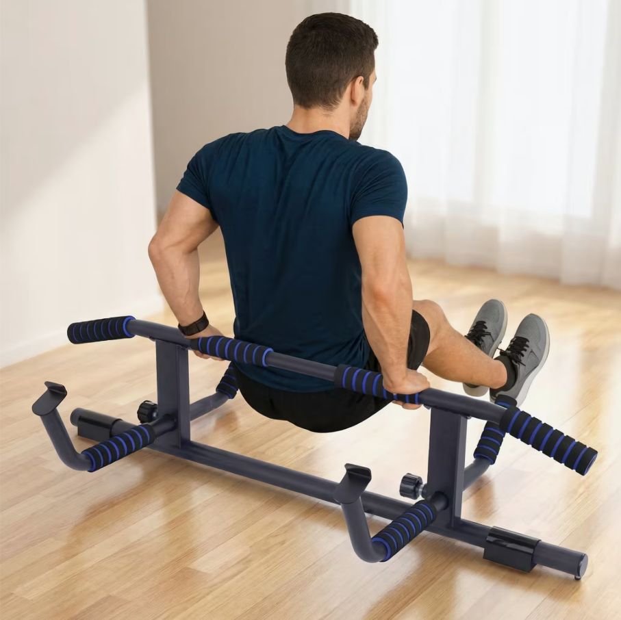 Mann trainiert an einer Klimmzugstange. Schwarze Metallkonstruktion mit blauen Griffen. Auf dem Boden stehend.