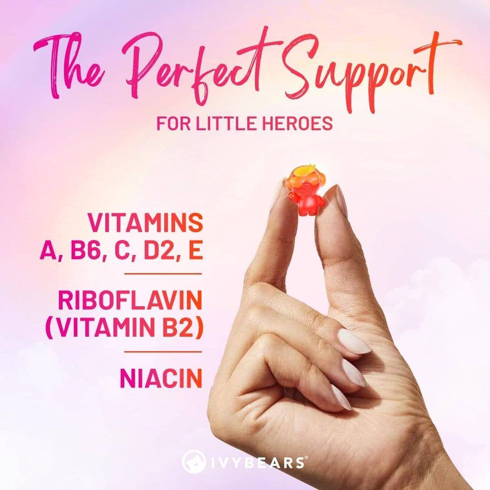 Hand hält ein rotes Gummibärchen. Text mit Vitaminen A, B6, C, D2, E, Riboflavin und Niacin.