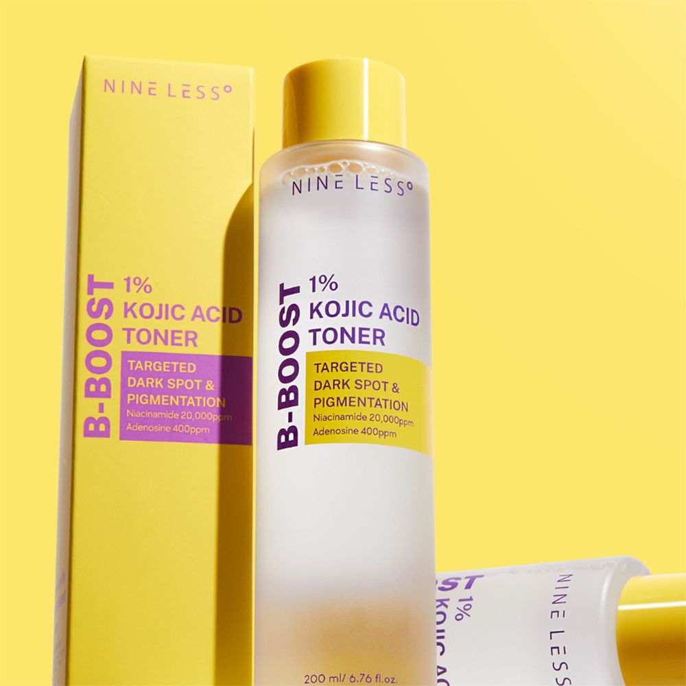 Produktflasche und Verpackung. Aufschrift: NINE LESS, B-Boost 1% Kojic Acid Toner. 200 ml. Gelber Hintergrund.