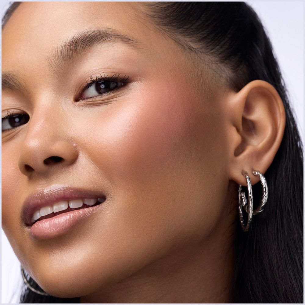 Nahaufnahme einer Frau mit Rouge auf der Wange. Keine Produkte oder Marken sichtbar.