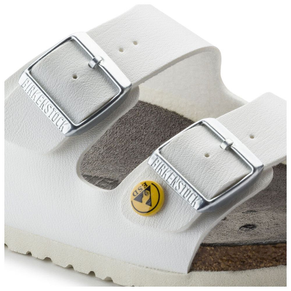 Nahaufnahme von weißen Sandalen mit zwei Schnallen. Marke Birkenstock und ESD-Symbol sichtbar.