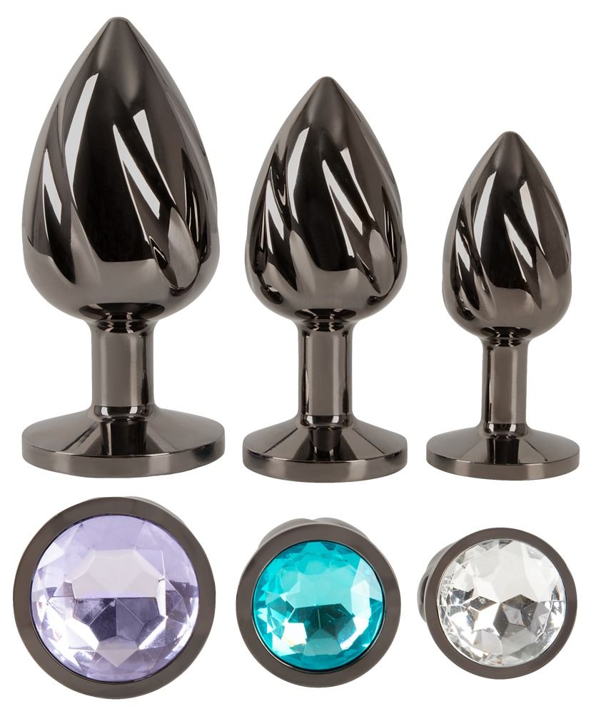 Drei Metall-Analplugs mit spiralförmiger Oberfläche und runden Schmucksteinen.