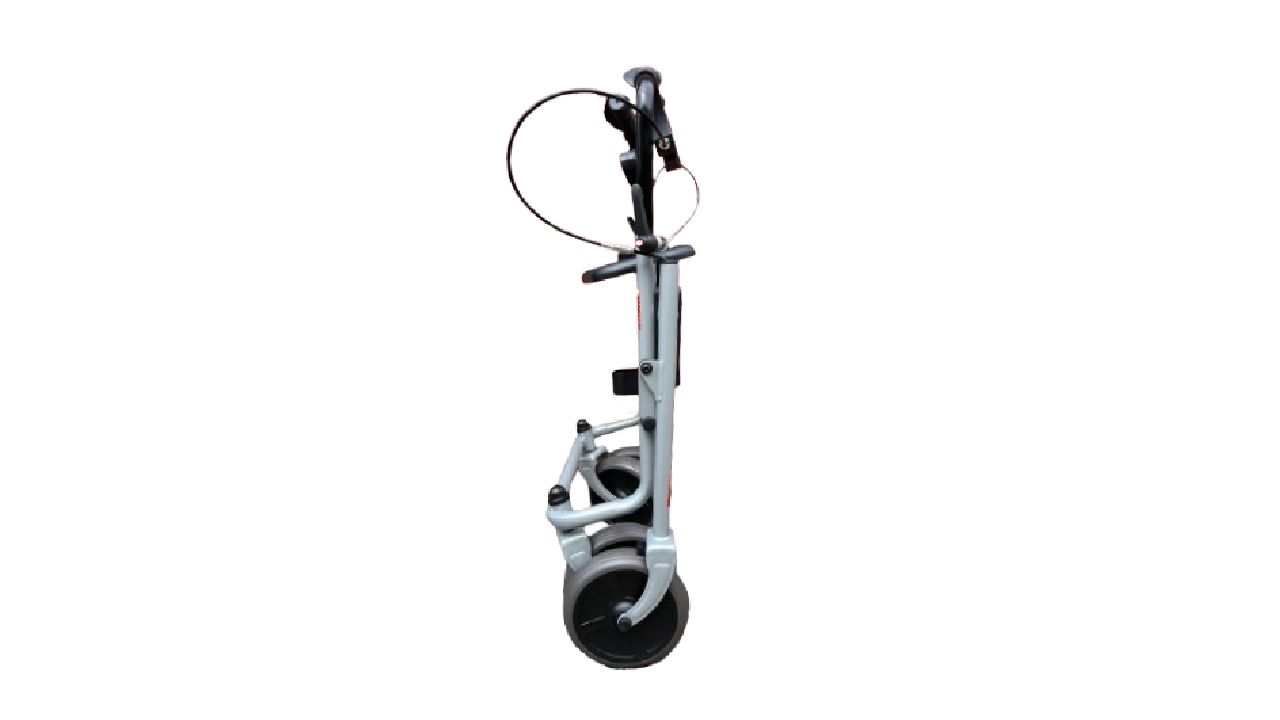 Gefalteter Rollator von der Seite. Graues Metallgestell, schwarze Räder. Bremsen und Griffe sichtbar.