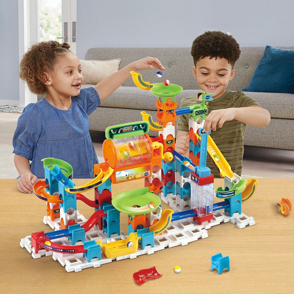 Mehrfarbiger Murmelbahn-Bausatz mit Kindern. Enthält Rampen, Trichter und rotierende Elemente. VTech Marble Rush.