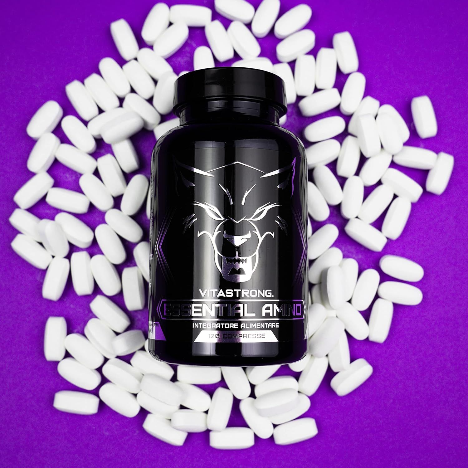 Schwarze Flasche Vitastrong Essential Amino, Tabletten drumherum. Aufschrift und Wolf Logo. Lila Hintergrund.