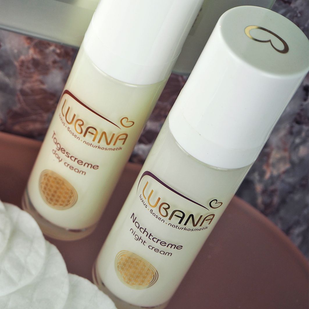 Zwei Creme-Flakons mit weißem Deckel. Aufschrift: Lubana Tagescreme und Nachtcreme. Auf rosa Untergrund.