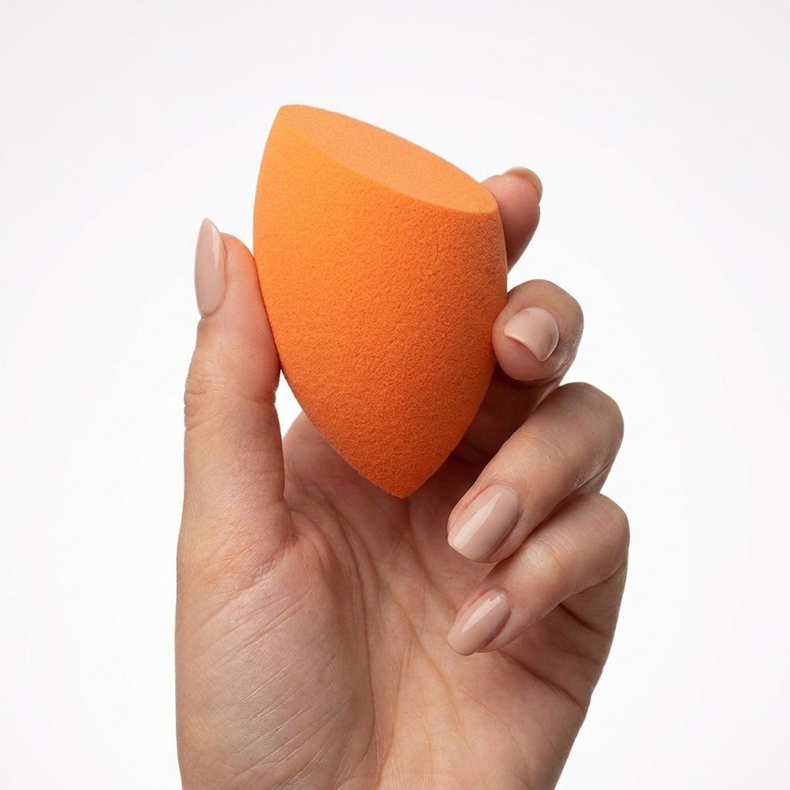 Orangefarbener Make-up-Schwamm mit abgeschrägter Spitze, gehalten in einer Hand.