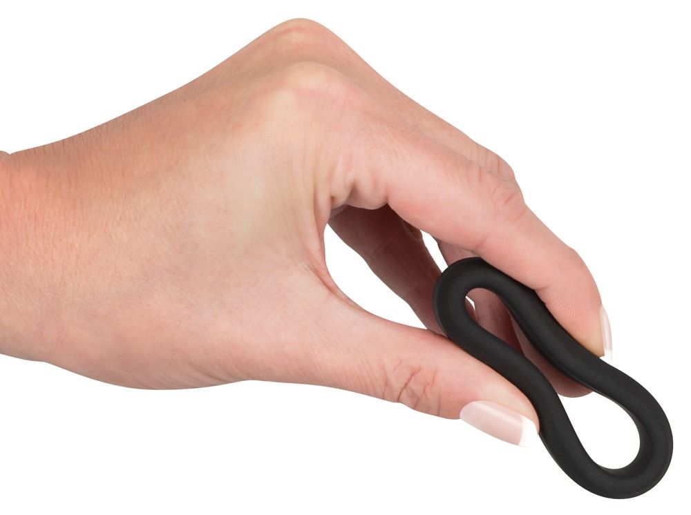 Schwarzer Penisring in einer Hand gehalten. Ring ist länglich.