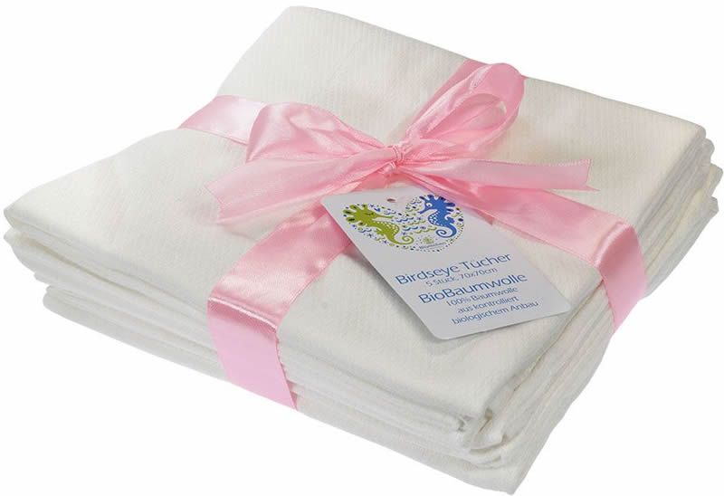 Stapel weißer Mulltücher, mit rosa Schleife gebunden. Etikett mit Text: Birdseye Tücher, BioBaumwolle. Quadratische Form.