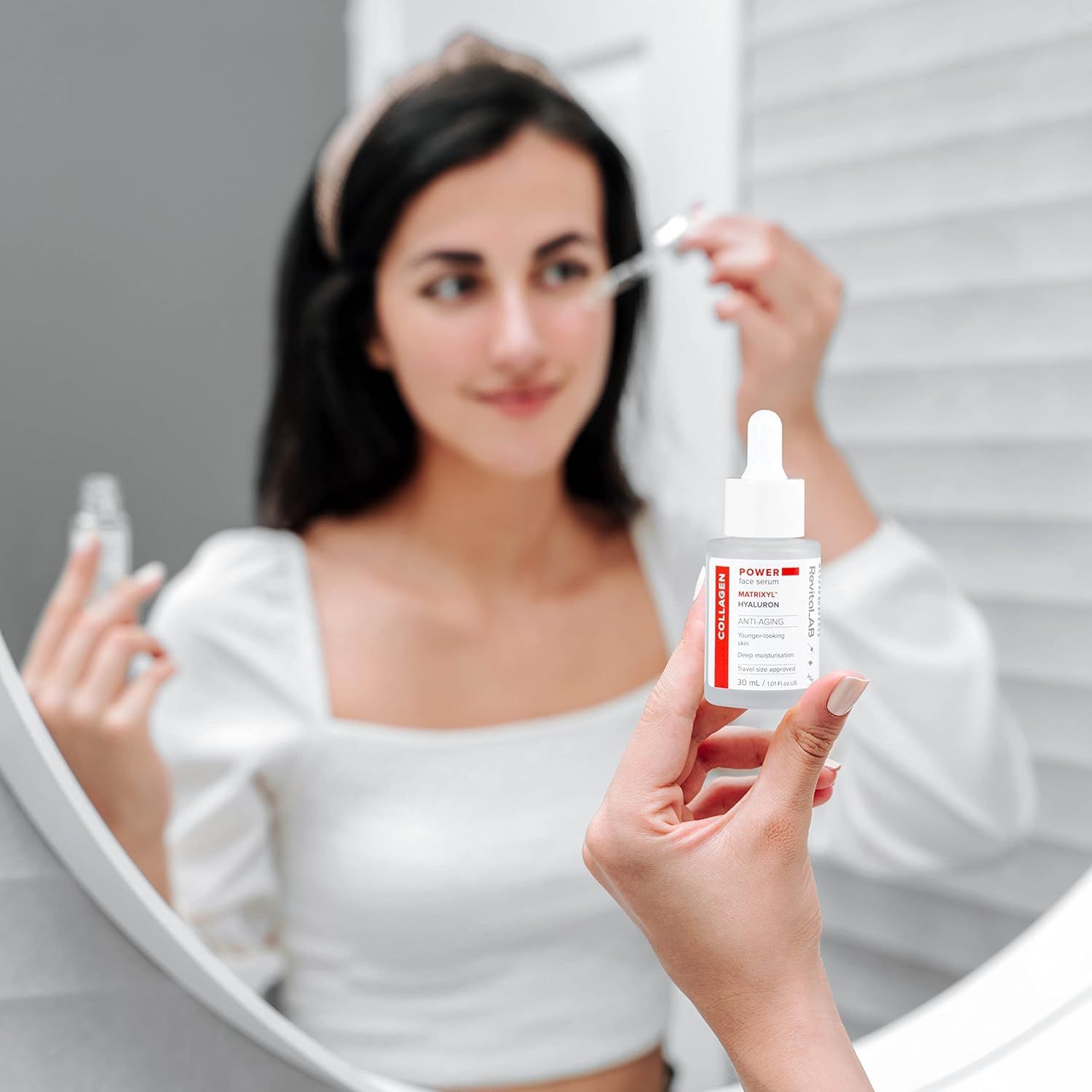 Frau betrachtet sich im Spiegel und hält eine Serumflasche. Flasche mit Spender, Aufschrift: POWER face serum.