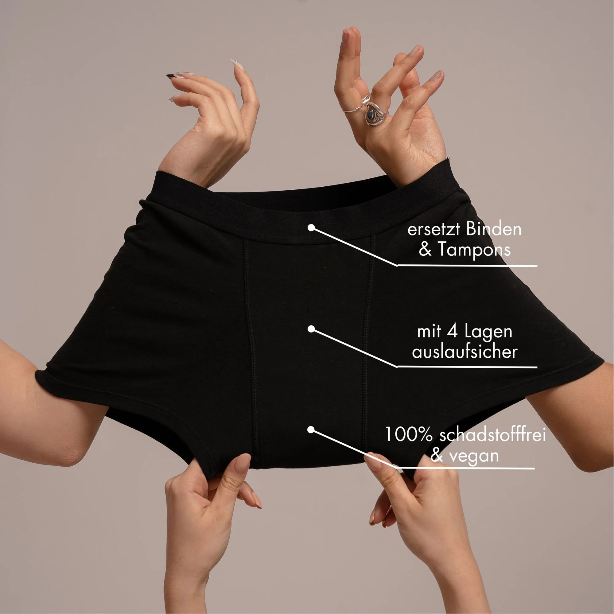 Schwarze Unterhose, von Händen gehalten. Text: ersetzt Binden & Tampons, mit 4 Lagen auslaufsicher, 100% schadstofffrei & vegan.