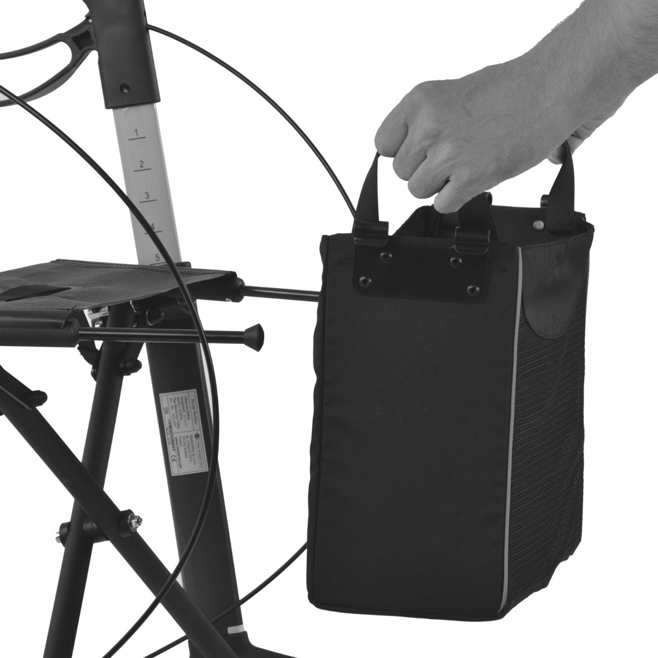 Schwarzer Korb eines Rollators. Hand hält Korb am Griff. Schwarzes Textilmaterial.