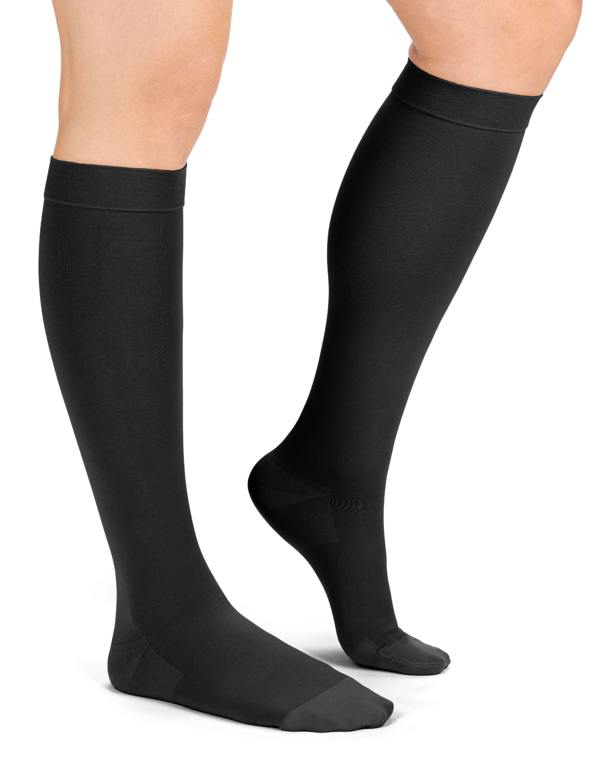 Beine mit schwarzen Kompressions-Kniestrümpfen. Strümpfe reichen bis unter das Knie. Schwarze Farbe.