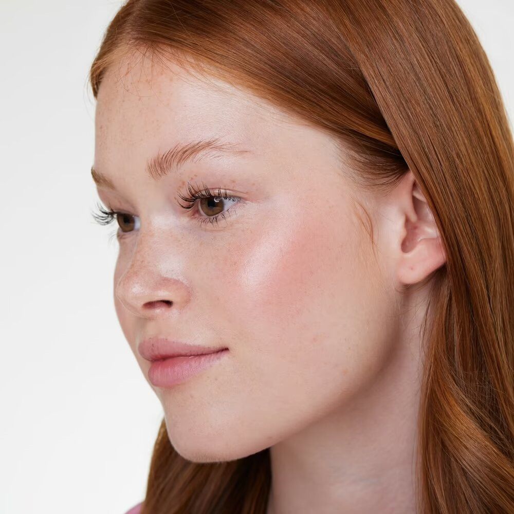 Porträt einer Frau mit roten Haaren. Sie hat Rouge auf den Wangen.