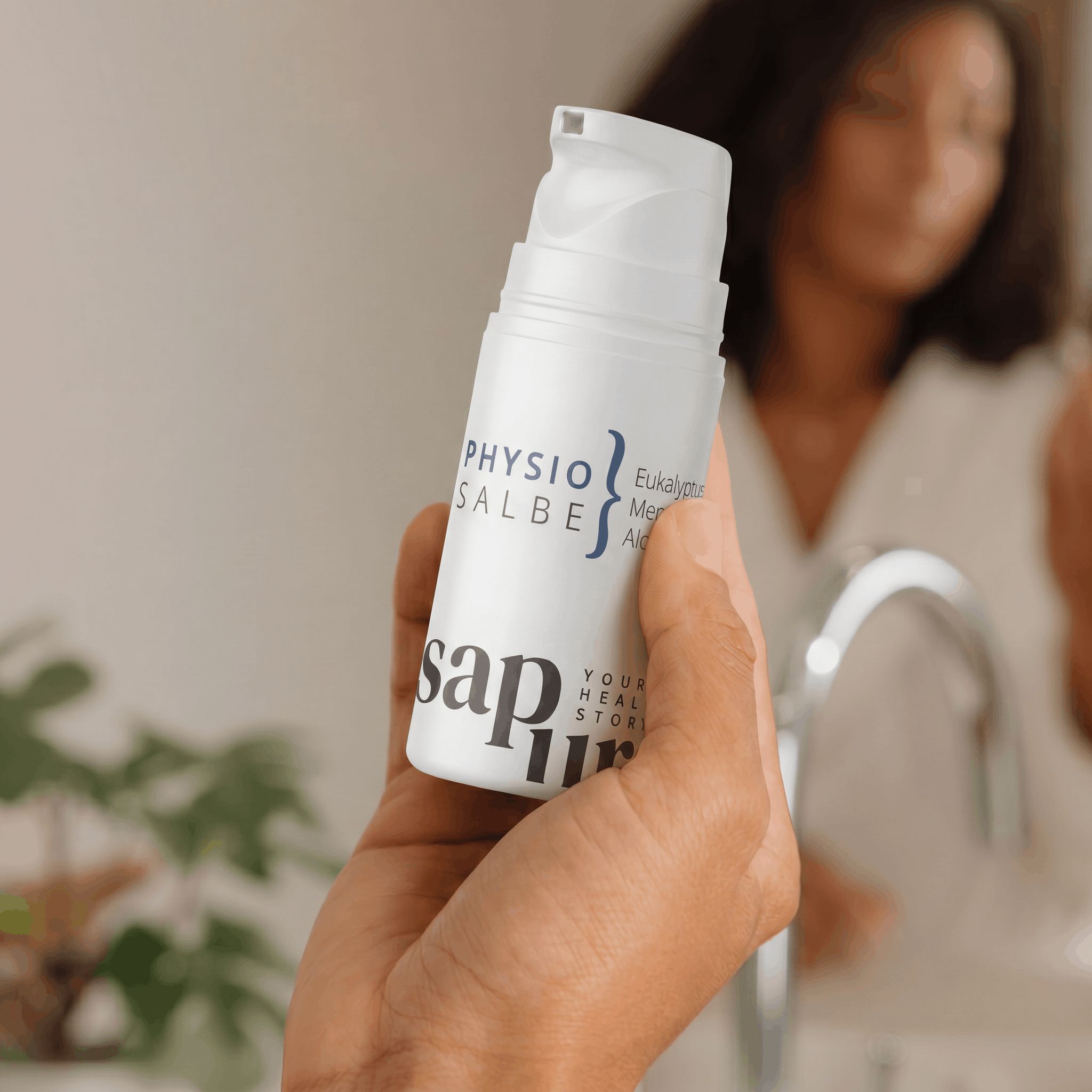 Hand hält weiße Flasche mit Pumpspender. Beschriftung: Physio Salbe, Eukalyptus, Menthol, Aloe Vera, sap pura.