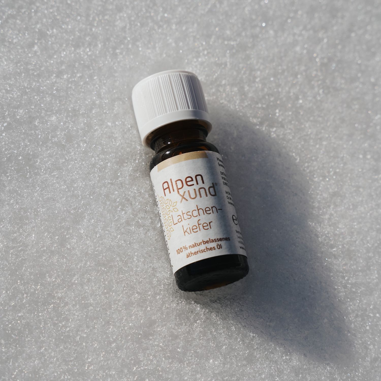 Braune Glasflasche mit weißem Deckel. Etikett mit Alpenxund, Latschenkiefer. Auf weißem Untergrund.