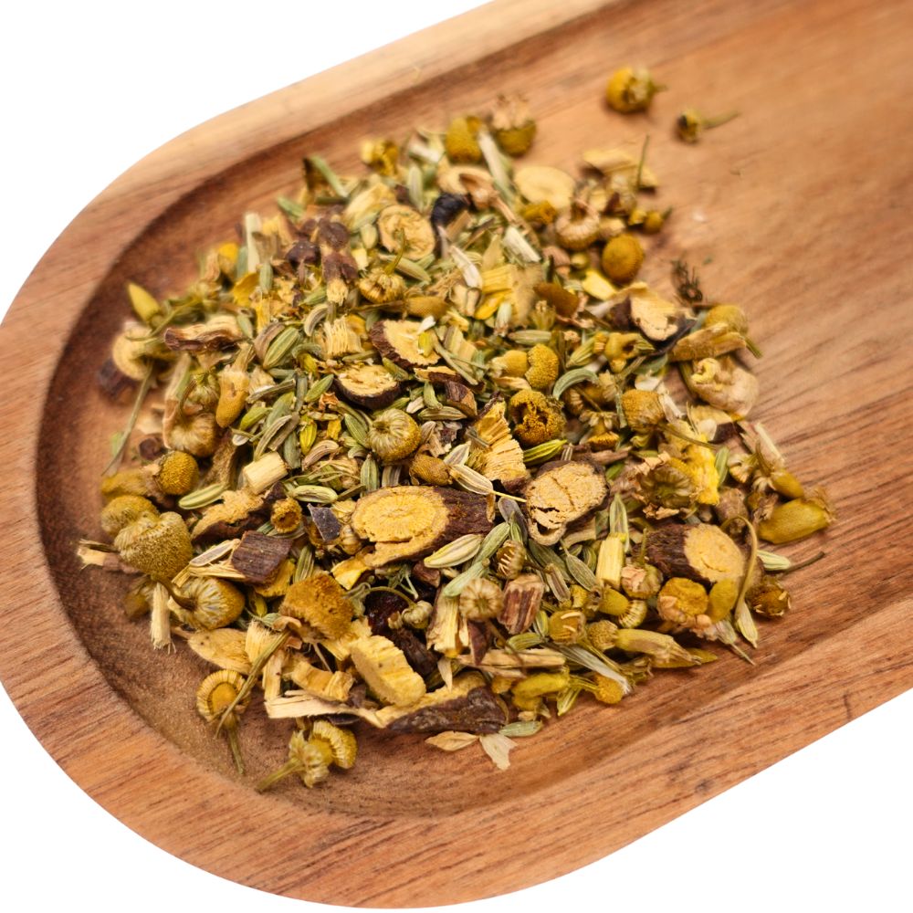 Verschiedene getrocknete Kräuter und Blüten in einer hölzernen Schale. Die Mischung enthält Kamillenblüten, Fenchelsamen und Wurzelstücke.