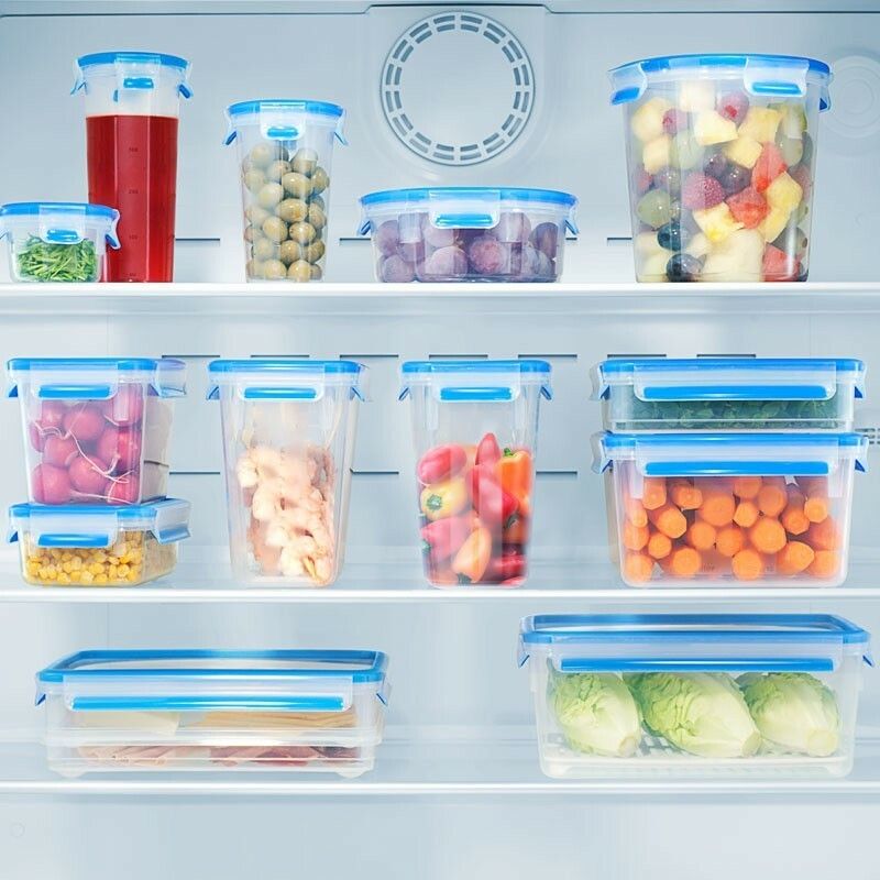 Kühlschrank mit verschiedenen Frischhaltedosen. Dosen mit blauem Deckel, gefüllt mit Lebensmitteln. Verschiedene Formen und Größen.