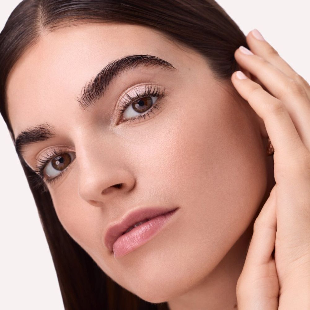 Nahaufnahme eines Gesichts mit geschminkten Augen. Die Augenlider sind mit Lidschatten bedeckt. Die Person berührt ihr Gesicht.